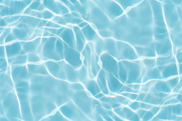 Blue water with ripples on the surface. Defocus blurred transparent blue colored clear calm water surface texture with splashes and bubbles. Water waves with shining pattern texture background.