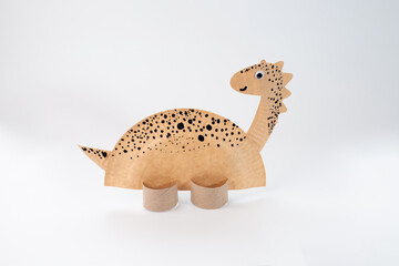 Charming paper craft dinosaur with long neck and tail. Made from disposable paper plate, standing on cardboard supports © Elena