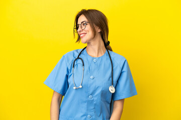 Surgeon doctor woman isolated on yellow background looking side