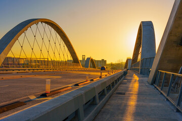 Obraz premium Sunset Skyline Over Modern Arched Bridge