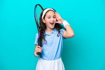 Little caucasian girl playing tennis isolated on blue background with surprise and shocked facial...