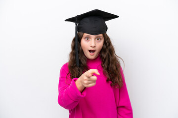 Little student girl wearing a graduated hat isolated on pink background surprised and pointing front