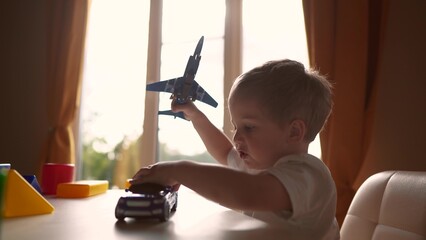 child baby playing with toys airplane car. happy family kid dream concept. child son on the table...