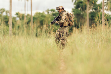 With M16 rifles in hand, soldiers patrol the dangerous jungle battlefield, surrounded by...