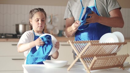 daughter and father washing dishes. happy family a kid dream concept. child daughter in an apron together with dad in the kitchen wash dishes help parents. baby baby washing lifestyle dishes