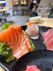 Salmon and tuna Sashimi on black plate in restaurant