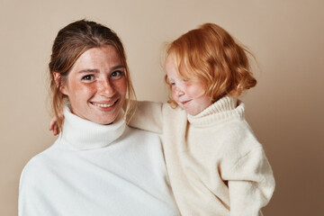 Mother and daughter bonding moment in cozy white sweaters during family trip to the countryside