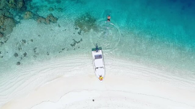 Aerial video of a tourist running and throwing himself into the clear blue sea from a boat, Banyak Island, Aceh Singkil