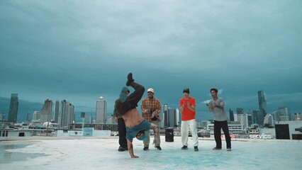 Hispanic hipster dancing surrounded by multicultural friend at city view with blue sky. Group of...