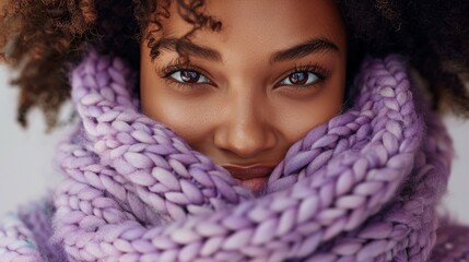  african american woman in smiling holding up a soft purple knitted wool sweater recently washed close to her face 