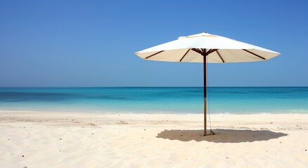 A white umbrella is on a beach with a blue ocean in the background. The scene is peaceful and relaxing