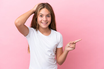 Little caucasian girl isolated on pink background surprised and pointing finger to the side