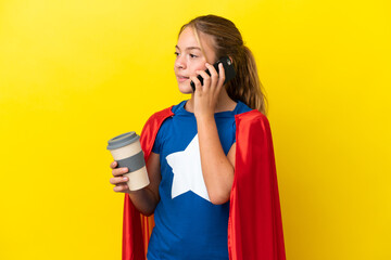 Super Hero little girl isolated on yellow background holding coffee to take away and a mobile