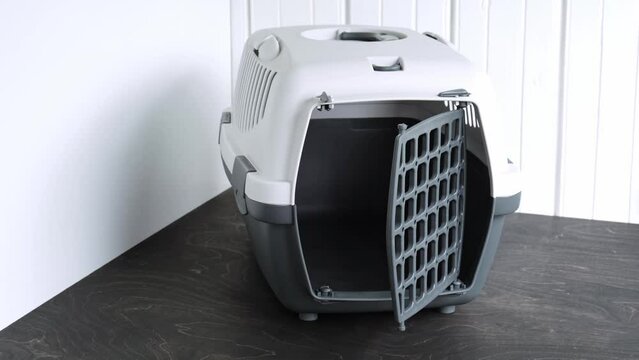 A new empty pet carrier of grey color. A plastic box for pets on a home background. Transportation of animals. High quality 4k footage