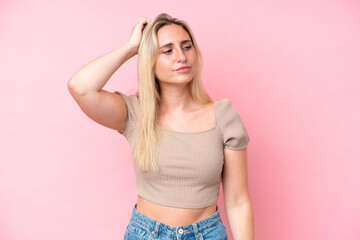 Young caucasian woman isolated on pink background having doubts while scratching head