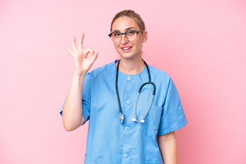 Young surgeon nurse woman isolated on pink background showing ok sign with fingers