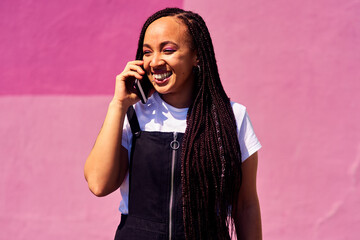 Phone call, happy and woman at wall for conversation, joke and comedy with streetwear on pink...