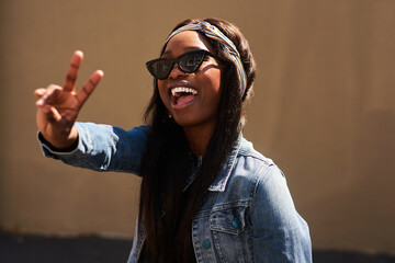 Peace sign, happy and black woman with streetwear with sunglasses, energy and excited in city. Gen...