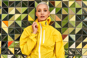 Woman, portrait and jacket in city with street clothes, green and yellow tile wall background....