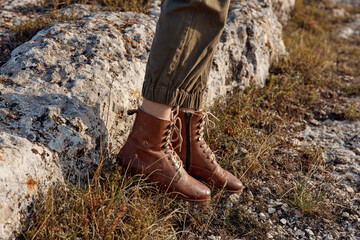 Traveler standing on top of rock in brown leather combat boots looking out at scenic view