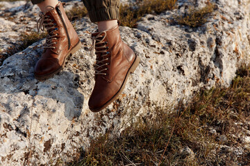 Journey through nature brown boots resting on rock in field with grass and rocks in background