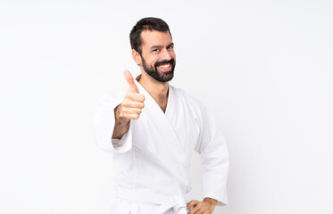 Young man doing karate over isolated white background with thumbs up because something good has...