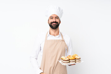 Young man holding muffin cake over isolated white background laughing