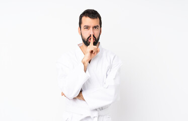 Young man doing karate over isolated white background showing a sign of silence gesture putting...