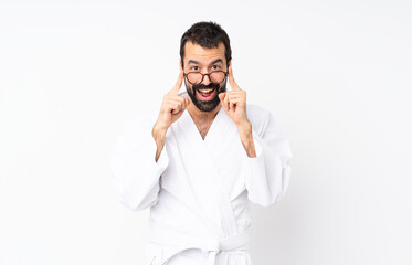 Young man doing karate over isolated white background with glasses and surprised