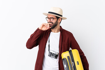 Traveler man man with beard holding a suitcase over isolated white background smiling a lot