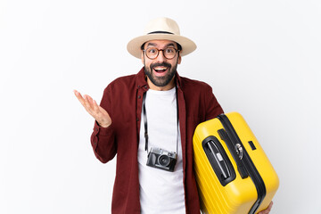 Traveler man man with beard holding a suitcase over isolated white background with shocked facial...