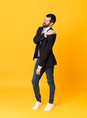 Full-length shot of business man over isolated yellow background suffering from pain in shoulder...