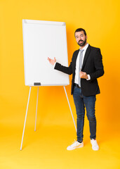 Full-length shot of businessman giving a presentation on white board over isolated yellow background