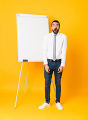 Full-length shot of businessman giving a presentation on white board over isolated yellow...