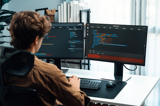 IT developer working online software development on pc monitors at modern home office on coding application screens, creating updated latest program firmware information version concept. Gusher.
