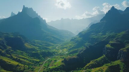 Fototapeta premium Sunlit green trees and rolling hills in a majestic mountain valley with clear skies above.