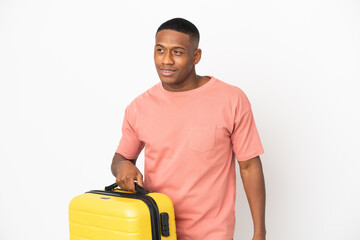 Young latin man isolated on white background in vacation with travel suitcase