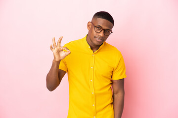 Young latin man isolated on pink background showing ok sign with fingers