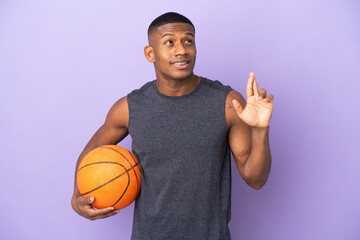 Young basketball latin player man isolated on purple background with fingers crossing and wishing...