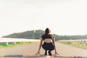 Healthy woman warms up before jogging and relaxes. Stretch your arms and look outside at the road,...