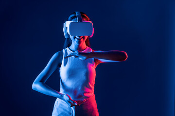 Smart Female standing surrounded by neon light wear VR headset connecting metaverse, futuristic...
