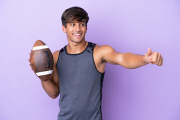 Young man playing rugby isolated on purple background giving a thumbs up gesture