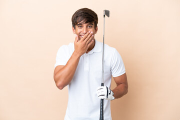 Young golfer player man isolated on ocher background happy and smiling covering mouth with hand