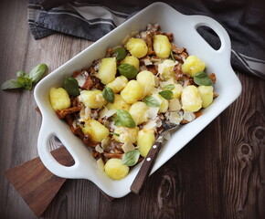 Italian dish, potato gnocchi with addition of herb pesto, cheese and mushrooms on cast iron frying pan