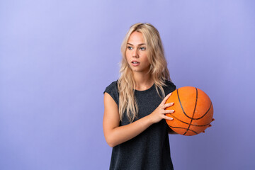 Young Russian woman isolated on purple background playing basketball