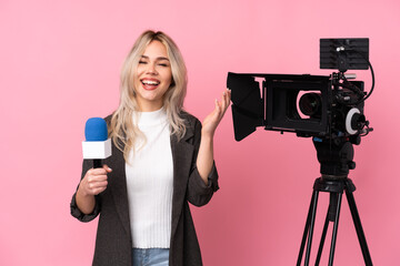 Reporter woman holding a microphone and reporting news over isolated pink background smiling a lot