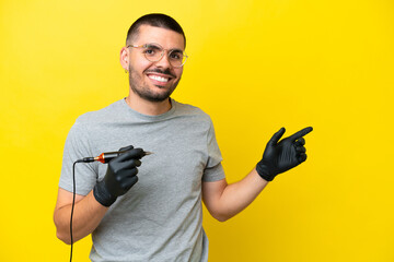 Tattoo artist caucasian man isolated on yellow background pointing finger to the side