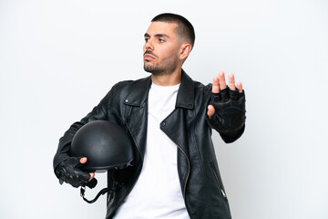 Young caucasian man with a motorcycle helmet isolated on white background making stop gesture and...