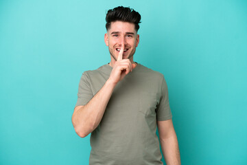Young caucasian man isolated on blue background showing a sign of silence gesture putting finger in...