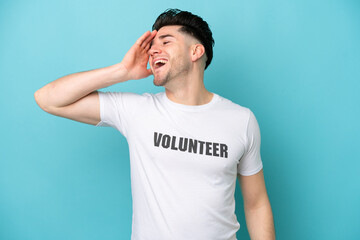 Young volunteer caucasian man isolated on blue background smiling a lot
